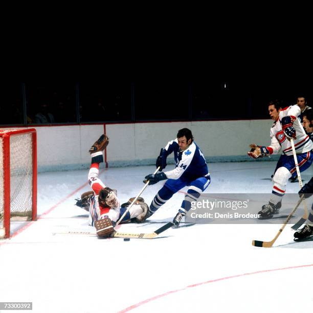 Dave Keon of the Toronto Maple Leafs skates for the puck against Ken Dryden of the Montreal Canadiens.