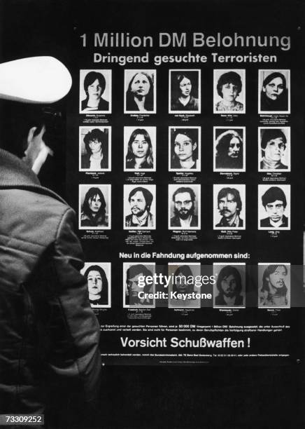 West-German policeman reading a wanted poster offering a one-million-mark reward for information leading to the capture of 20 members of the...