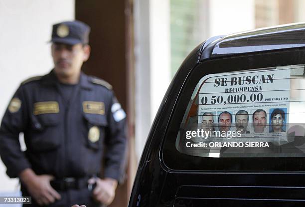Un agente de la Policia Nacional Civil permanece junto a un afiche con las fotografias de 15 profugos de la justicia vinculados a la quiebra de Banco...