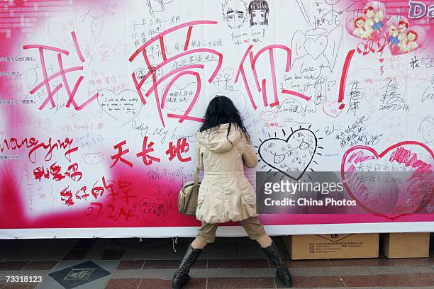Woman writes her oath of love on a billboard on February 14, 2007 in Beijing, China. Valentines Day is a traditional boon to flower sellers across...