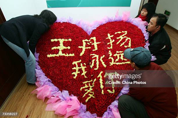 Workers move a heart shaped arrangement of roses with the Chinese words "Wang Dan, I will love you forever" at a flower shop on February 14, 2007 in...