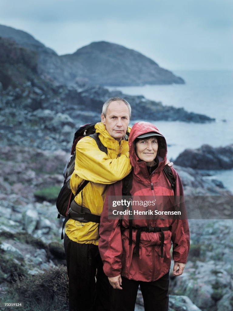 Mature man leaning on woman on nature trail in rain