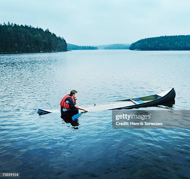 man sitting in sinking kayak, side view - sinking foto e immagini stock