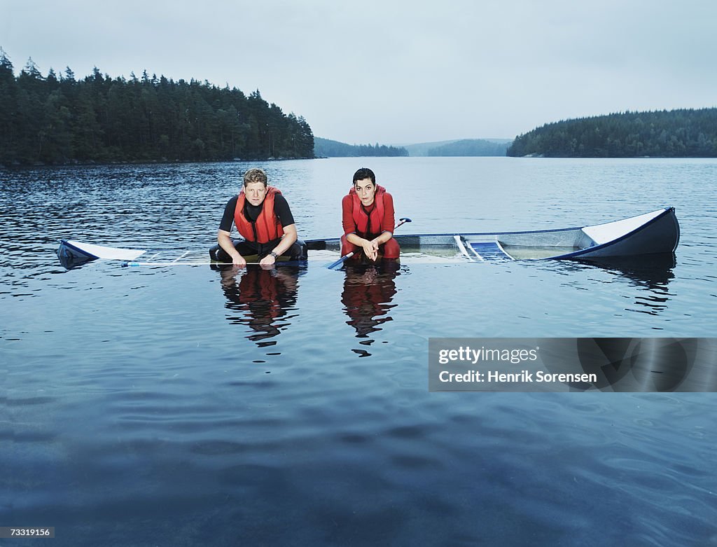 Man and woman sitting in sinking canoe