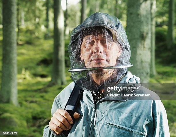 man wearing mosquito netting in forest - mosquito netting stock-fotos und bilder