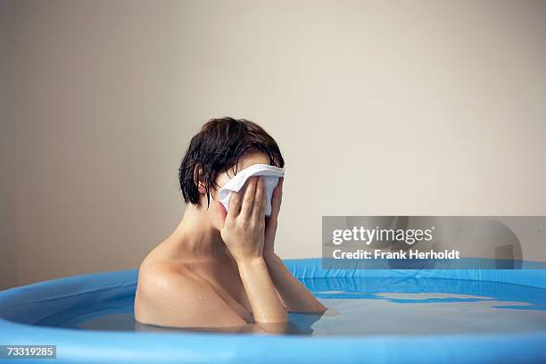 woman washing face in birthing pool - home birth stock-fotos und bilder