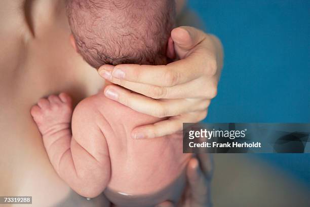 newborn baby boy (0-3 months) in birthing pool, rear view - swimming pool and hand stock-fotos und bilder