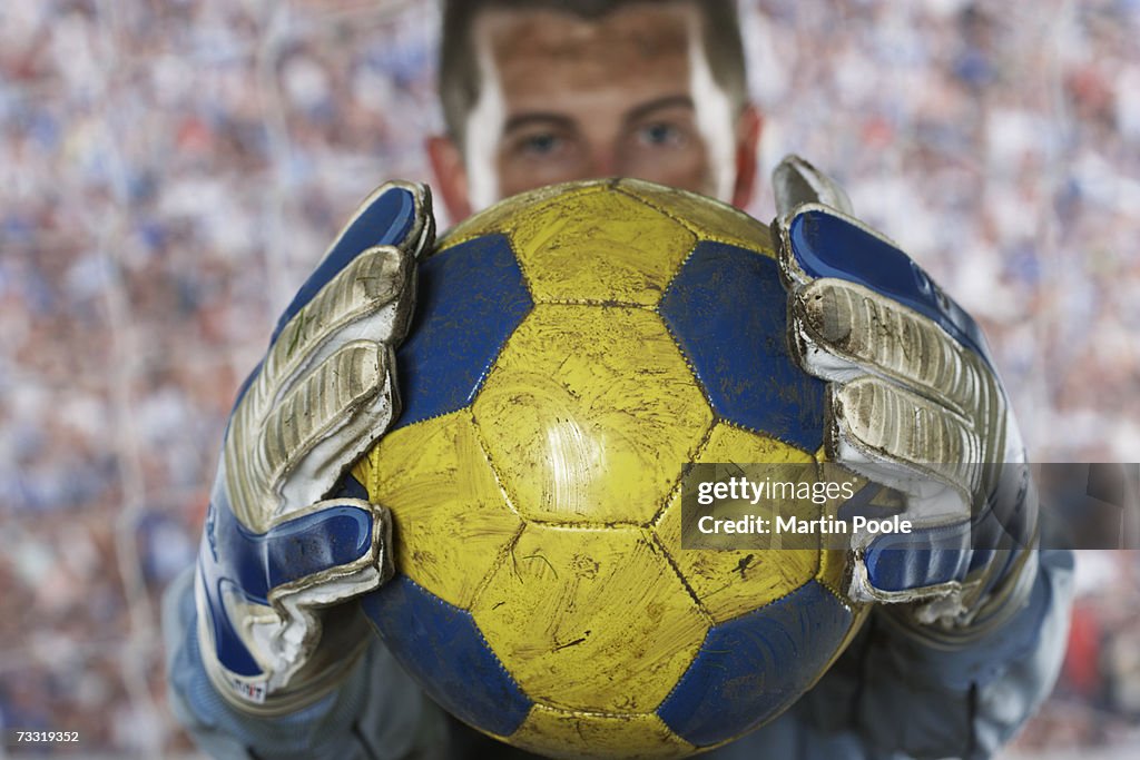 Soccer goalie holding soccer ball in goal, focus on ball