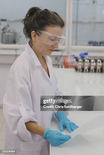 lab technician reading report in laboratory - laboratory report stock pictures, royalty-free photos & images