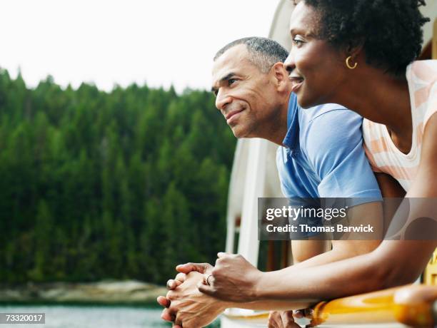 mature couple on deck of yacht looking at view, smiling - couple travel middle age ストックフォトと画像