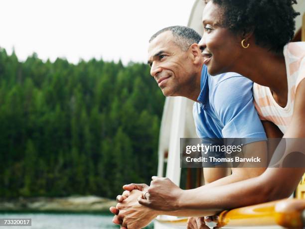 mature couple on deck of yacht looking at view, smiling - mature men group stock pictures, royalty-free photos & images