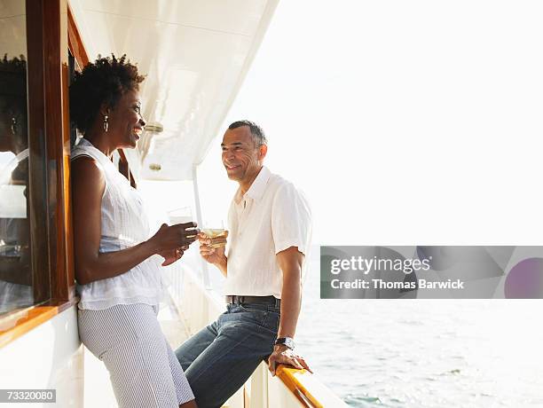 mature couple with drinks on deck of yacht - couple boat stock pictures, royalty-free photos & images