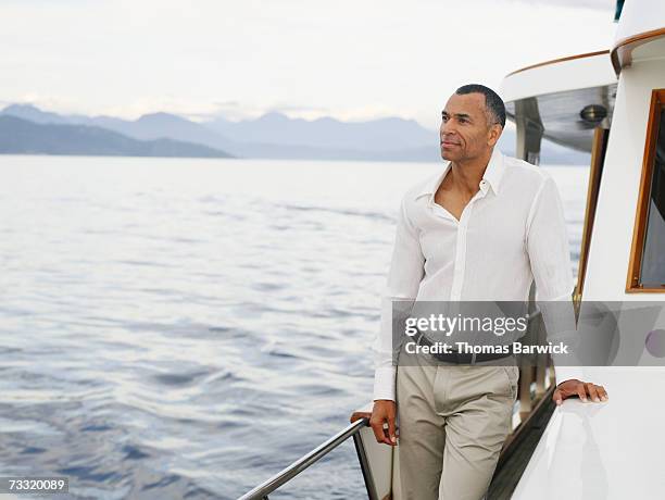 mature man looking at view from deck of yacht - abundância - fotografias e filmes do acervo