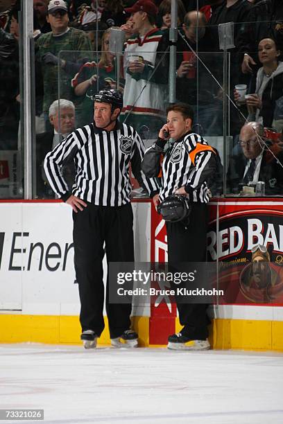 Referee Kelly Sutherland listens on the phone next to linesman Pat Dapuzzo for a review of a goal in action between the Minnesota Wild and the...