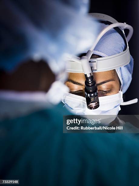 female doctor in scrubs with head light in surgery - surgeon stock pictures, royalty-free photos & images