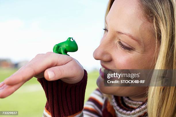 young woman with a toy frog on the back of her hand, close-up - woman frog hand stockfoto's en -beelden