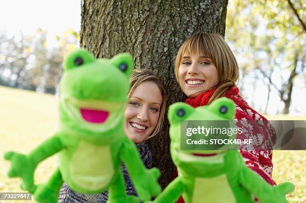 two young women with frog hand puppets, selective focus - woman frog hand stockfoto's en -beelden