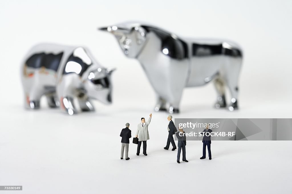 Businessmen figurines in front of bull and bear