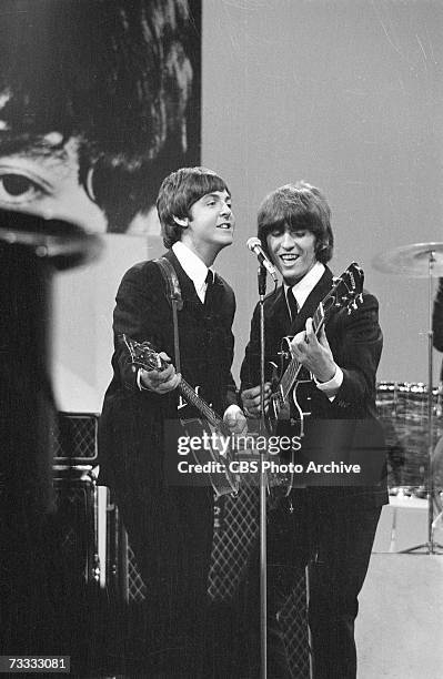 Members of the British rock band The Beatles, Paul McCartney and George Harrison , sing into a microphone as they play their instruments at the...