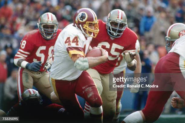 John Riggins of the Washington Redskins carries the ball with Laurence Pillars and Keena Turner of the San Francisco 49ers trying to catch him during...