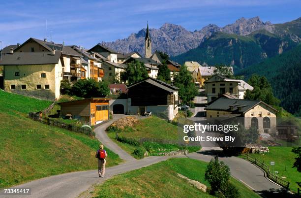 hiker walking towards small mountain village of guarda, lower engadine valley, switzerland - ガルダ ストックフォトと画像