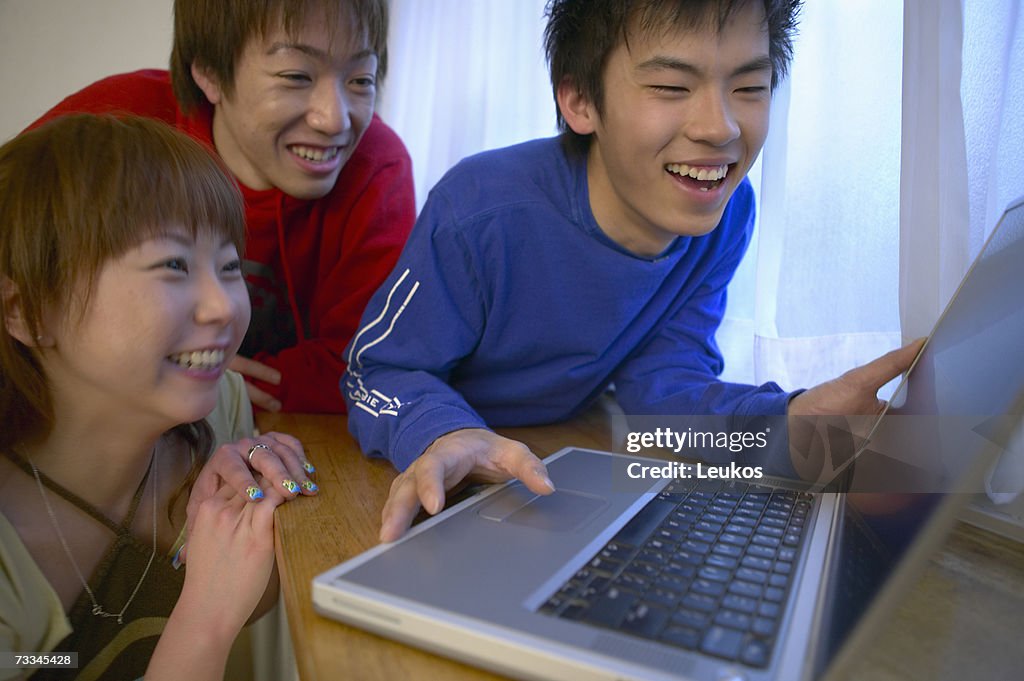 Teenagers (16-18) laughing around laptop