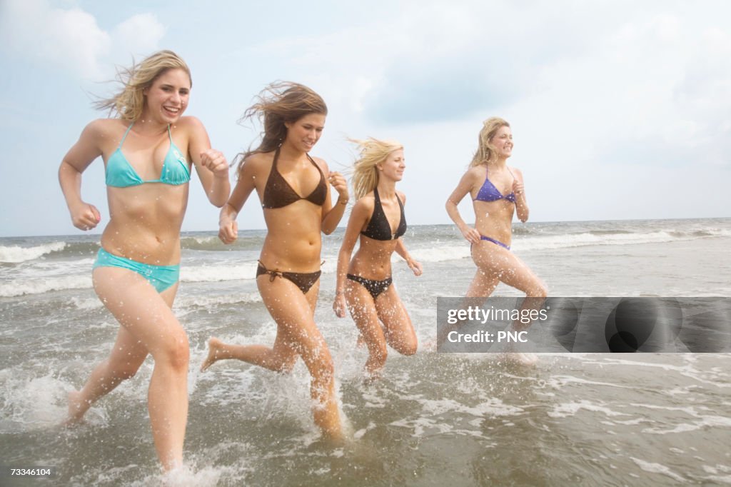 Four teenage girls (16-17) running into sea