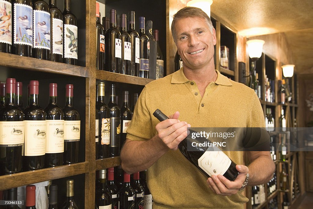 Man holding bottle of wine in wine shop, portrait