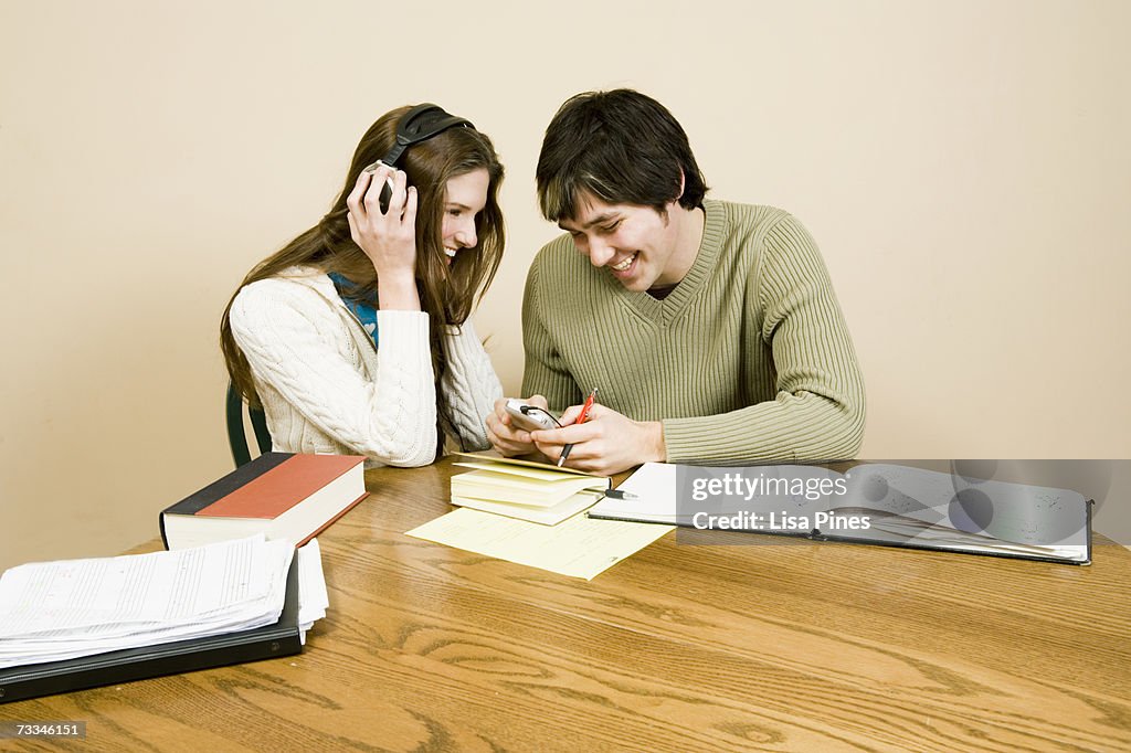 Young couple studying at home, woman listening to MP3 player