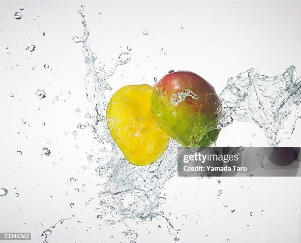 two mango halves being splashed with water - mango splash stock pictures, royalty-free photos & images