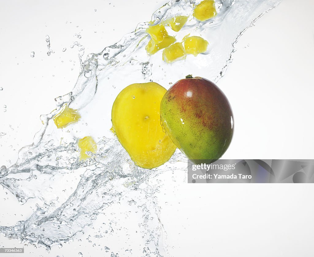 Two mango halves being splashed with water