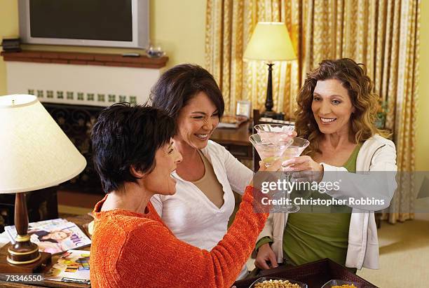 three women toasting with cocktails at home - girls' night in stock pictures, royalty-free photos & images