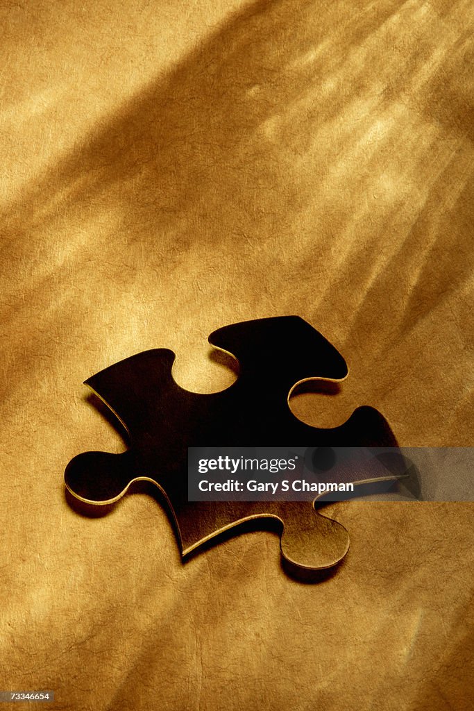 Jigsaw piece over textured paper, elevated view (digital composite)