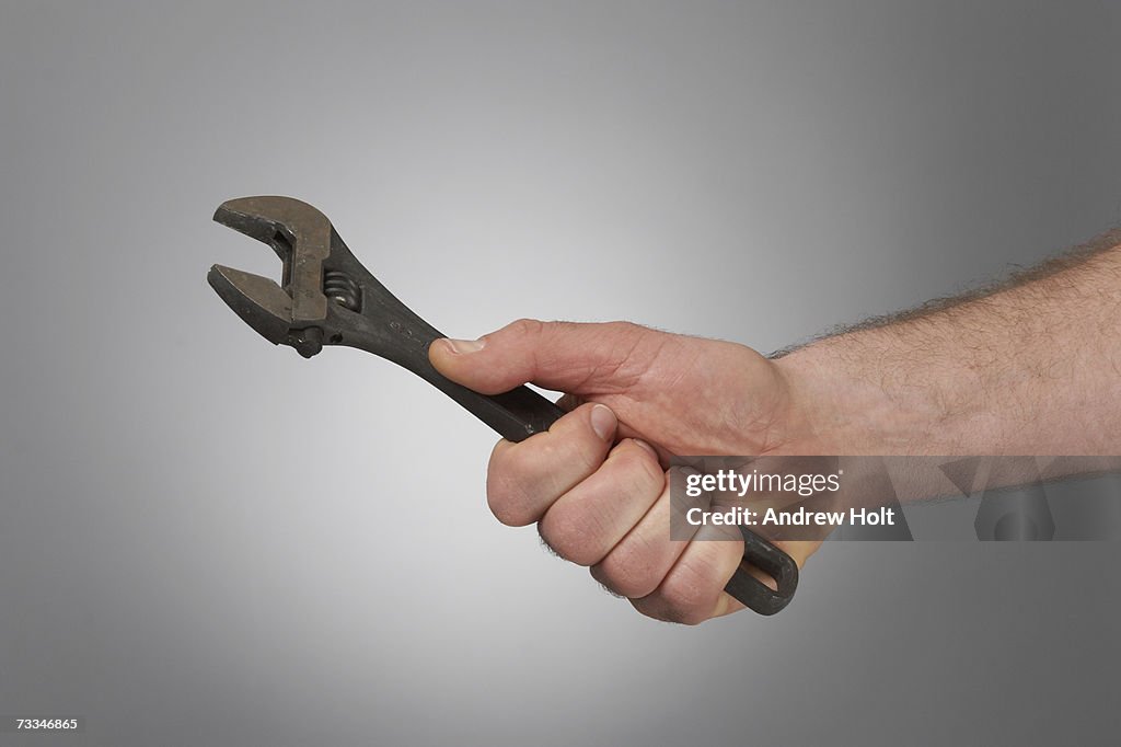 Man holding adjustable wrench close-up