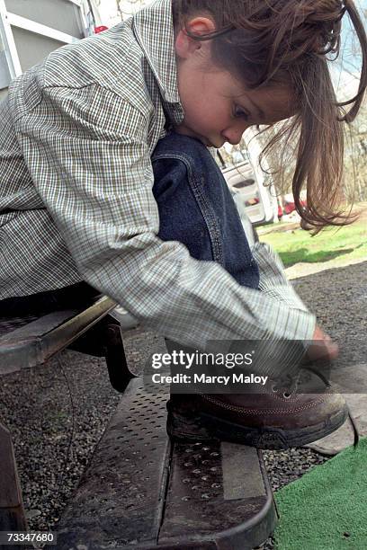 young cowboy (8-9) tying shoelace, outdoors - lace fastener stock pictures, royalty-free photos & images