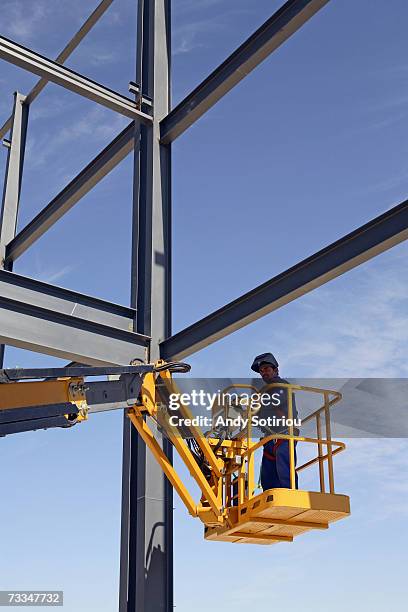 worker standing in cherry picker at construction site - cherry picker stock pictures, royalty-free photos & images