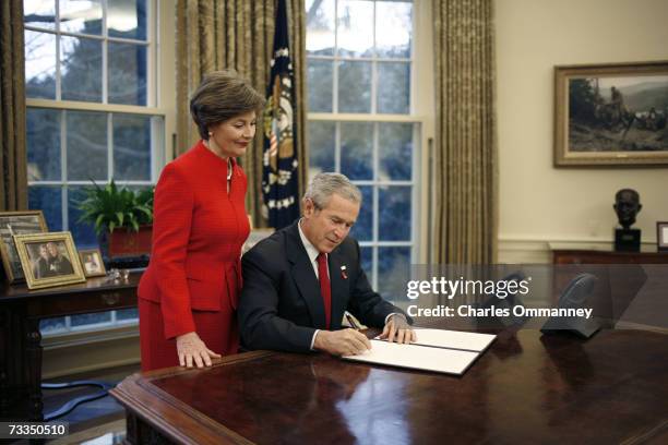 First Lady Laura Bush looks on as US President George W. Bush signs a Presidential Proclamation in the Oval Office of the White House on February 1,...