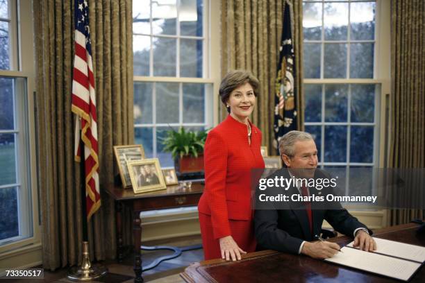 First Lady Laura Bush looks on as US President George W. Bush signs a Presidential Proclamation in the Oval Office of the White House on February 1,...