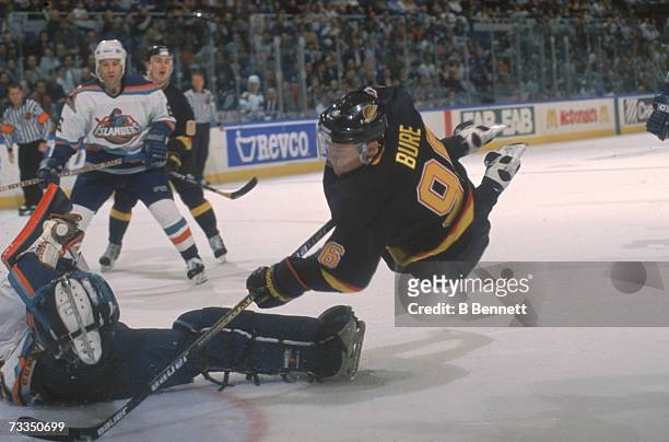 Russian hockey player Pavel Bure of the Vancouver Canucks sails through the air as he tries to score on the New York Islanders goalie, Uniondale, New...