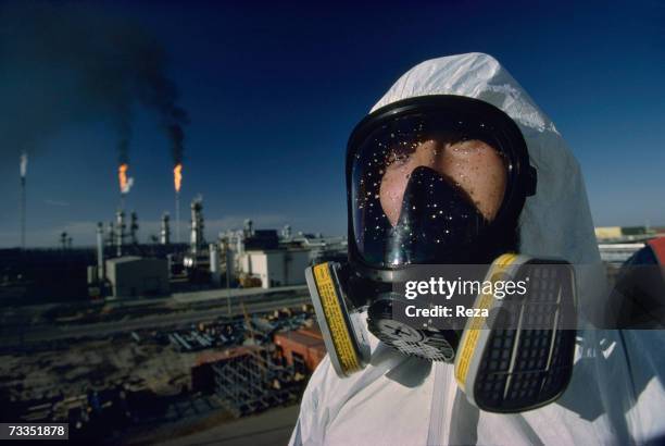 Korean oil worker, wearing a chemical protection safety suit with gas mask, prepares to clean gas tanks at the Tengiz oil field, on the northeastern...