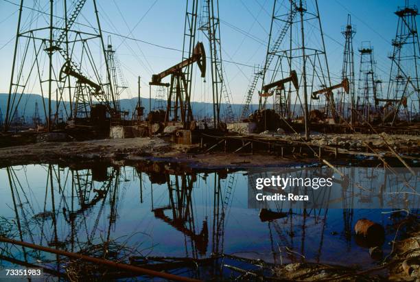 Rusted oil derricks and pools of polluted water remain exactly where they were abandoned during early 20th century oil exploration and industry, near...