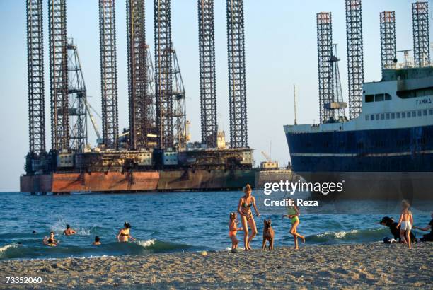 Despite pollution from the region's petrochemical industry, Russian women and children bathe on the shore of the Caspian Sea just adjacent to looming...