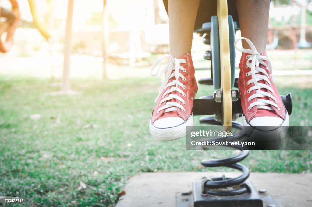 Low Section Of Girl Sitting On Spring Ride At Park