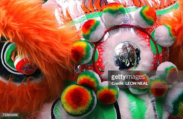 London, UNITED KINGDOM: The Chinese New Year parade revellers are reflected in a dragon mask during the traditional celebrations in London's...