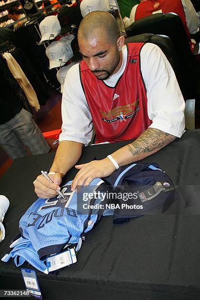 Carlos Boozer of the Utah Jazz signs autographs and greets customers during an appearance for NBA All-Star Week at Champs Sports Goods at the Las...