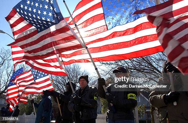 People hold flags during the funeral for Marine Captain Jennifer J. Harris outside St. John the Evangelist Church February 19, 2007 in Swampscott,...