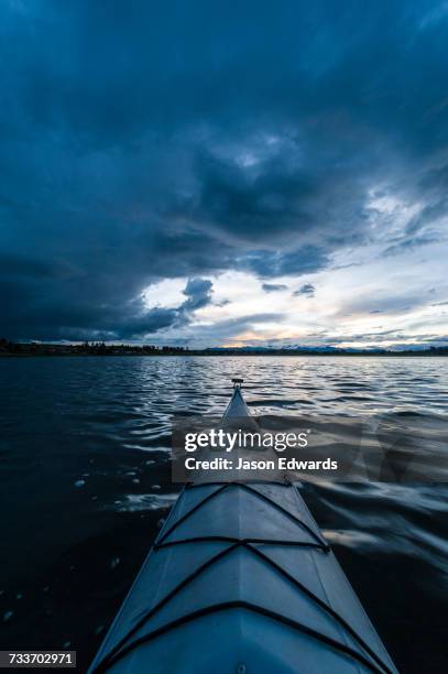 a canoe bow on a still lake in the andes mountains beneath storm clouds. - piuray lake stock pictures, royalty-free photos & images