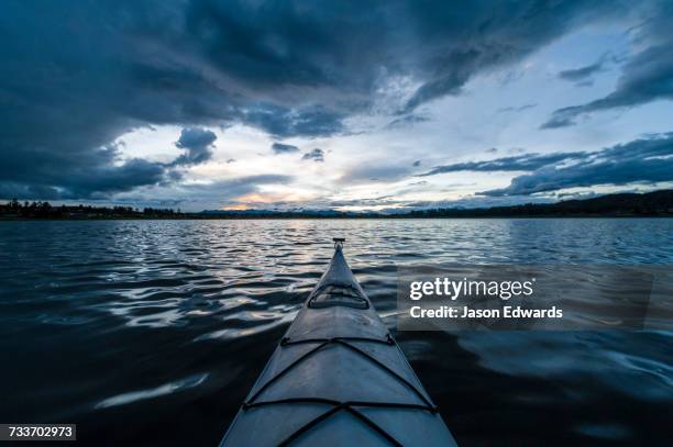 a canoe bow on a still lake in the andes mountains beneath storm clouds. - piuray lake stock-fotos und bilder