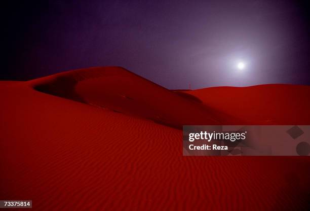 Full moon rises over the red sand dunes just outside the Saudi Aramco oil field complex facilities at Shaybah in the Rub' al Khali desert on March...