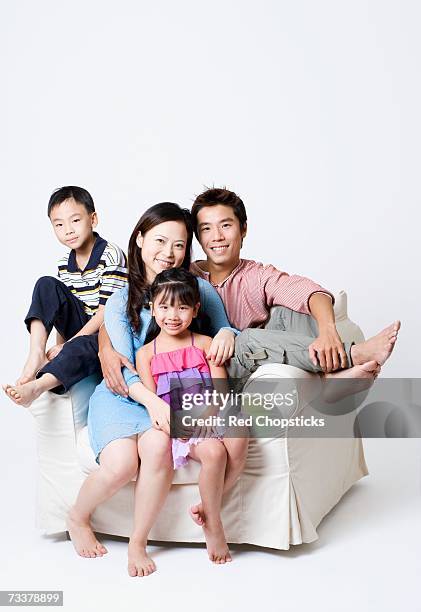 portrait of a mid adult man and a young woman sitting in an armchair with their son and daughter - front view portrait of four children sitting on rock stock-fotos und bilder